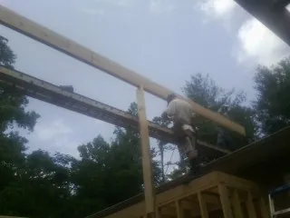 Carpenter setting a ridge beam over a new addition frame — Ice Dam Removal by Roofing Brothers in Treynor