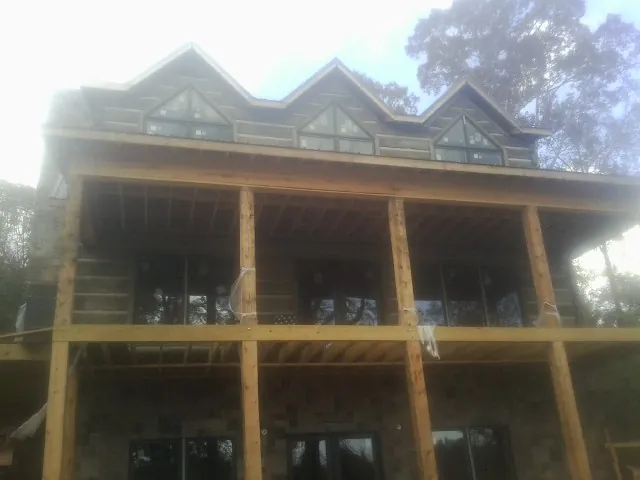 Dormers and porch framing on a large log home under construction — Roof Coating work by our crew in Treynor