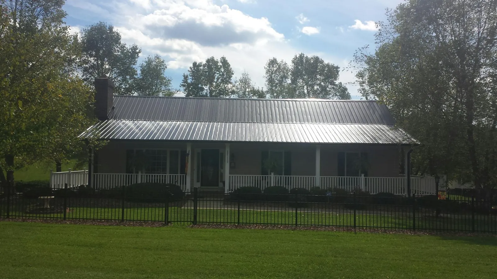 Gray metal roof on a brick ranch with a full width front porch — Gutter Guard Installation work by our crew in Treynor