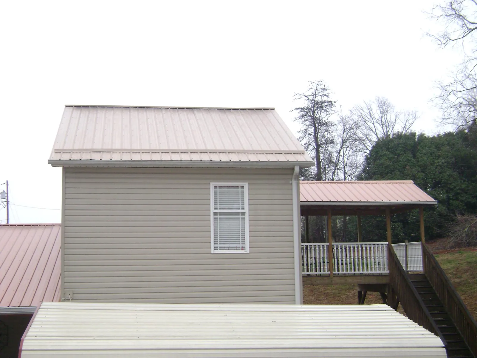 Tan metal roofs on a two story addition and attached porch, from a Roof Replacement job in Treynor
